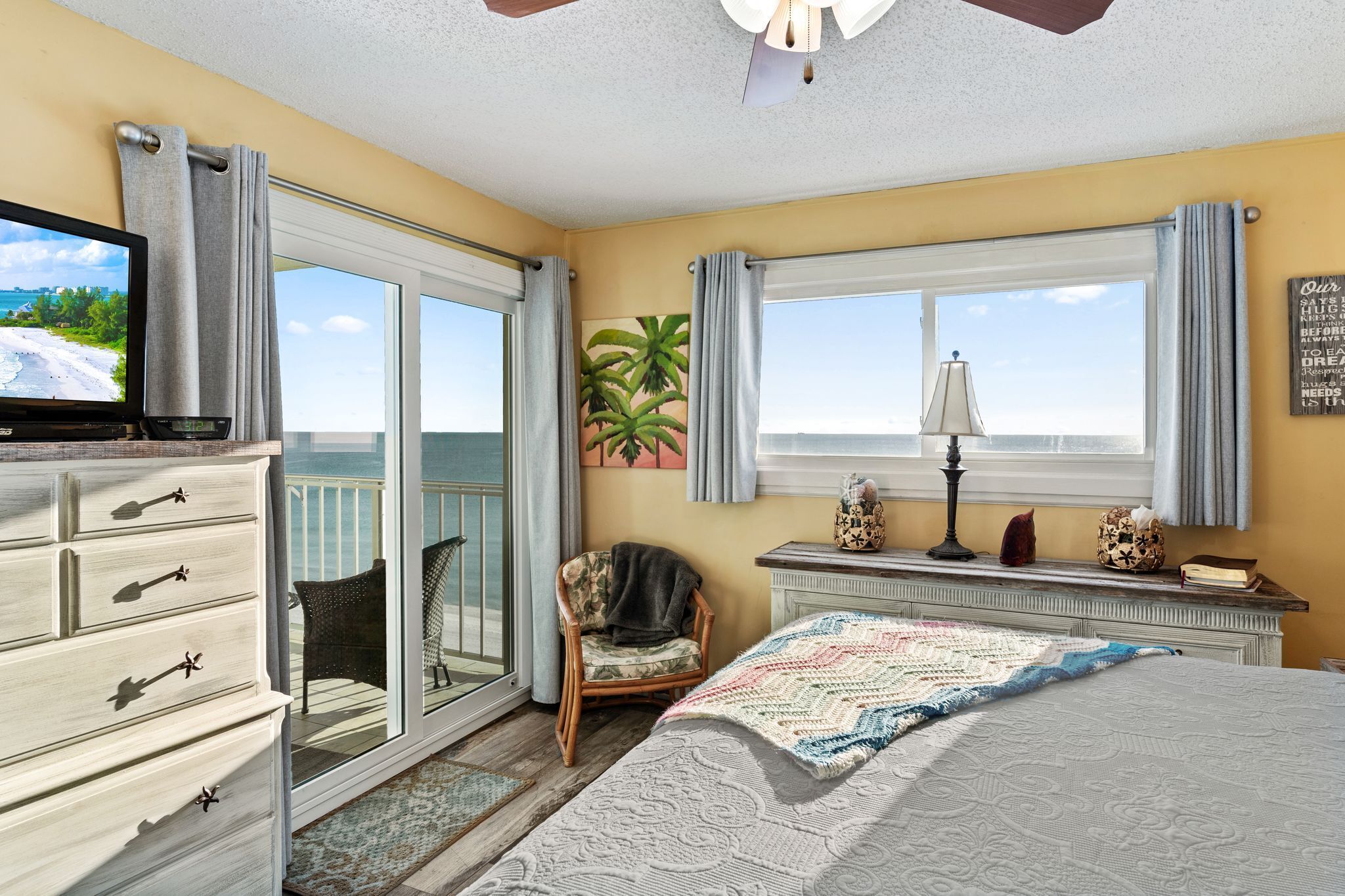 A bedroom with a bed, a dresser, a chair, a television, and a window with curtains.