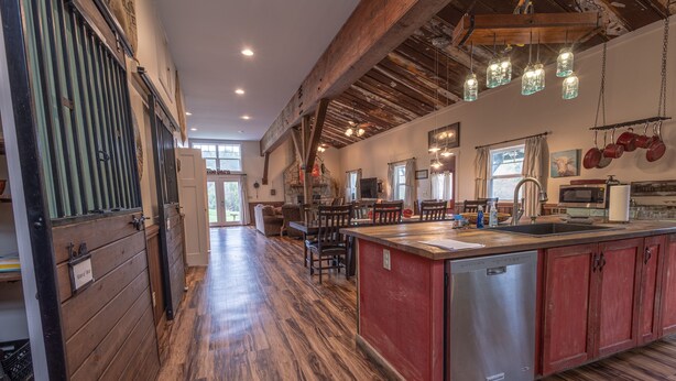 Una cocina amplia con una isla central, suelo de madera y techo rústico.