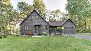 A two-story house with a garage, surrounded by a well-maintained lawn and trees.