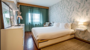 Un dormitorio con cama, escritorio, silla, lámpara y estante en la pared.