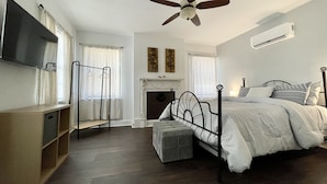 A bedroom with a bed, a ceiling fan, a fireplace, and a mounted TV. - Point on Pollock - Brewery Row - Brim of Downtown (New Bern)