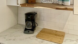 A kitchen with white cabinets, a coffee maker, and a sign that reads "Fresh Brewed Coffee." - Point on Pollock - Brewery Row - Brim of Downtown (New Bern)