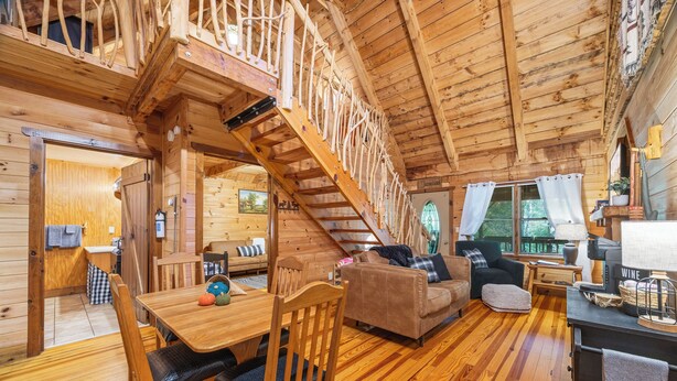 L'intérieur d'un chalet en bois comprend un coin repas, un canapé et un escalier.