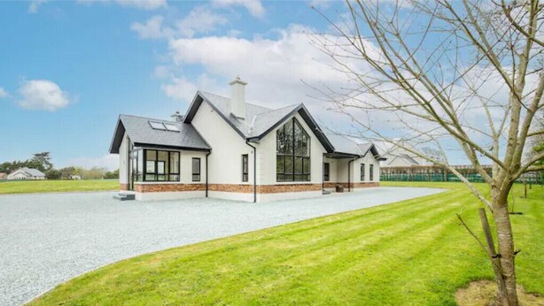 A modern house with a large driveway and a well-maintained lawn.