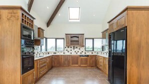 A spacious kitchen with wooden cabinets, a central island, and a large window.