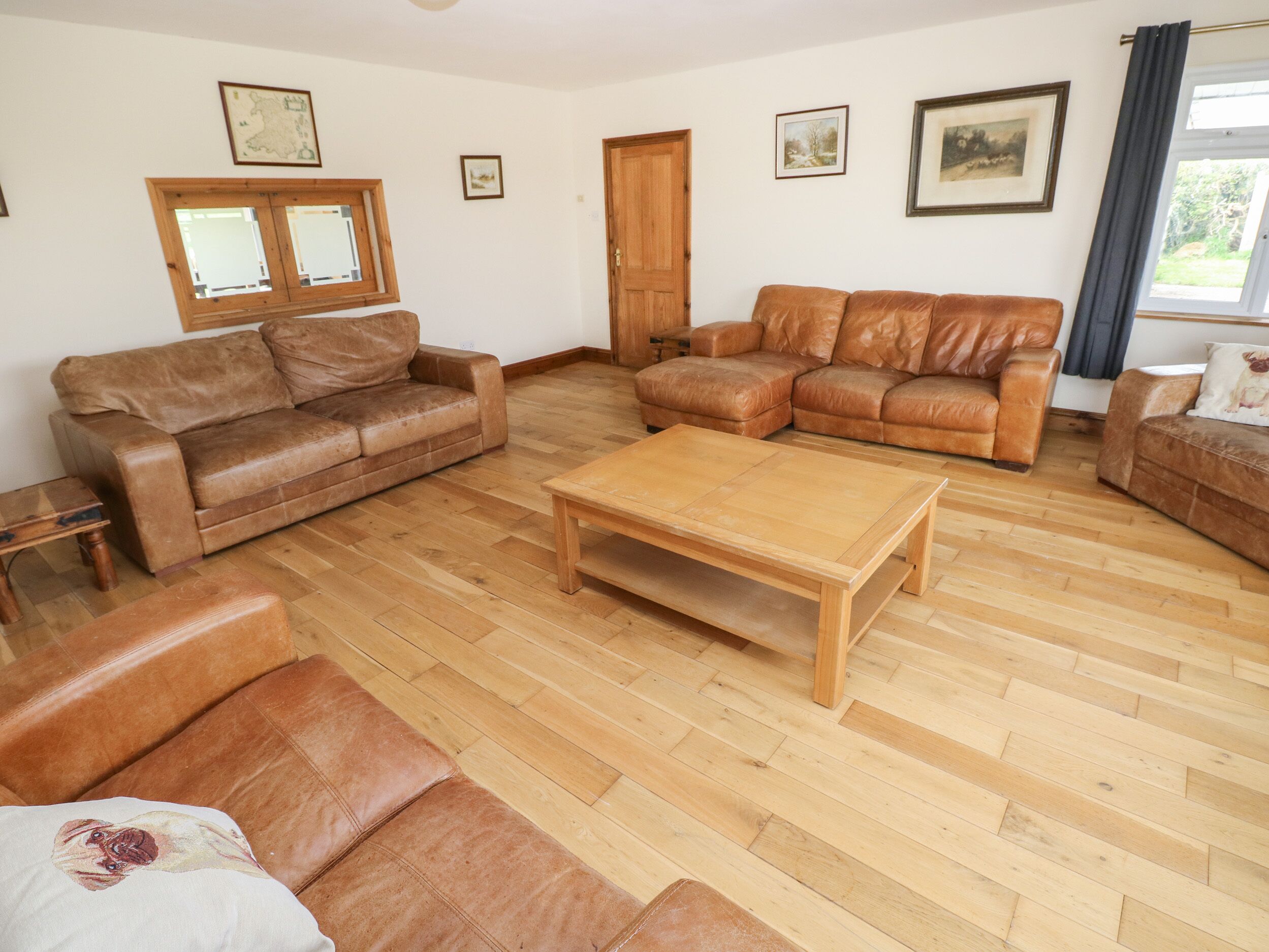 A living room with two brown leather sofas, a wooden coffee table, and a wooden floor.