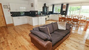 A modern kitchen with white cabinets, a black countertop, and a built-in oven. - Ty Mawr (Haverfordwest)