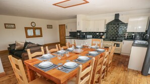 A dining area with a wooden table set for six, surrounded by wooden chairs. - Ty Mawr (Haverfordwest)
