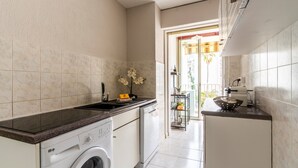 Une cuisine compacte équipée d’un lave-linge, d’un lave-vaisselle et d’un plan de travail avec un évier.