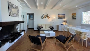 Una sala moderna con chimenea, un sofá, una mesa de comedor con sillas y una zona de cocina al fondo.