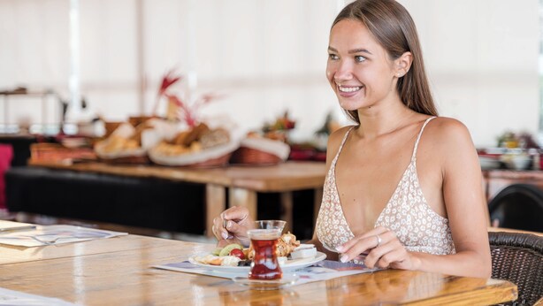 A woman sitting at a table with a plate of food and a glass of drink. - Far Life Hotel (Konyaalti)