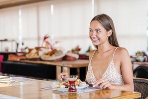 A woman sitting at a table with a plate of food and a glass of drink. - Far Life Hotel (Konyaalti)