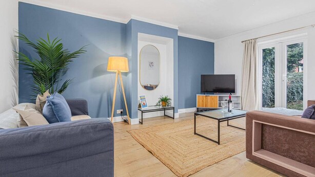 A modern living room with a sofa, a coffee table, a floor lamp, and a television. - 3 Bed House Sleeps 8 -near Heathrow -free Parking (Hounslow)