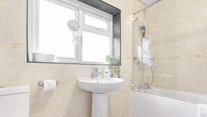 A bathroom with a white sink, a mirror, a toilet, and a shower area. - 3 Bed House Sleeps 8 -near Heathrow -free Parking (Hounslow)