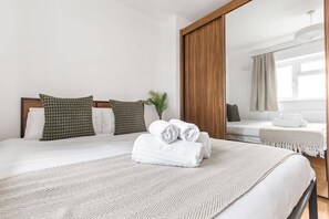A hotel room with a large bed, a wooden wardrobe, a mirror, and a window. - 3 Bed House Sleeps 8 -near Heathrow -free Parking (Hounslow)