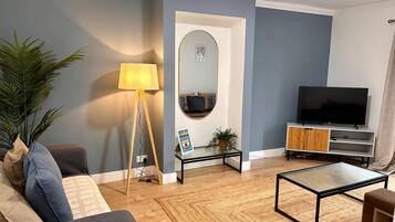 Un salon comprenant un canapé, une table basse, un lampadaire, un téléviseur et un miroir.