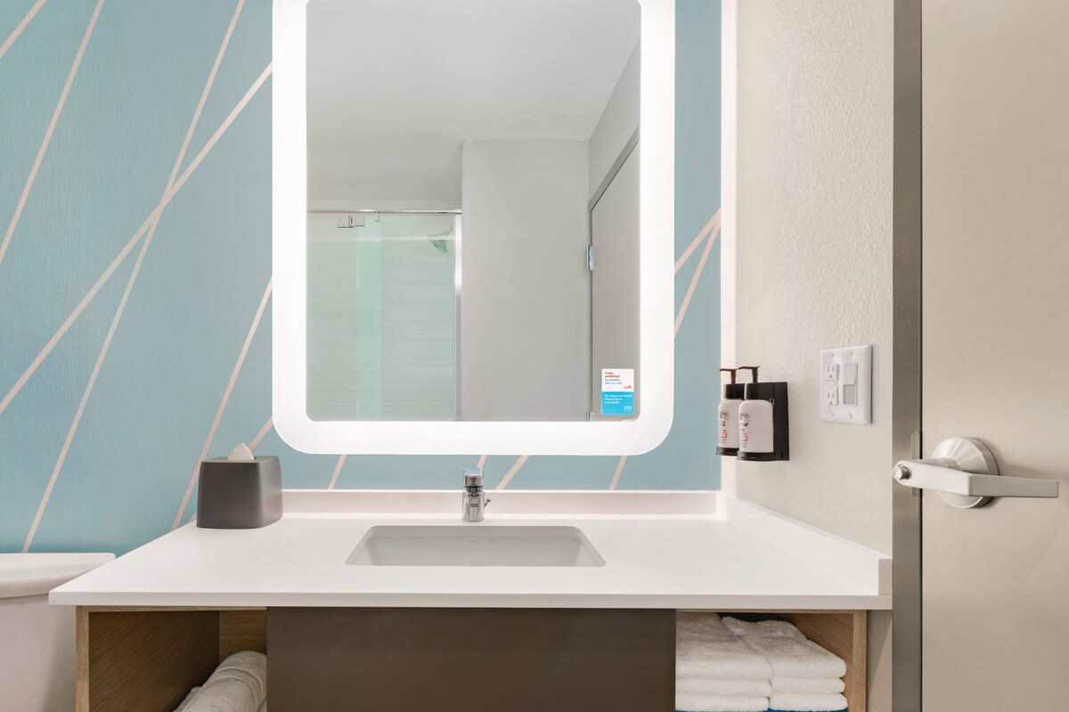 A bathroom with a white sink, a mirror, and a towel rack.