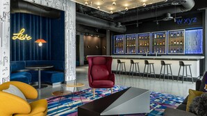 A modern bar area with a bar counter, multiple seating options, and a decorative neon sign. - Aloft by Marriott San Pedro Sula (San Pedro Sula)