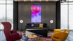A modern living room with a sofa, two armchairs, a coffee table, and a large abstract painting on the wall. - Aloft by Marriott San Pedro Sula (San Pedro Sula)