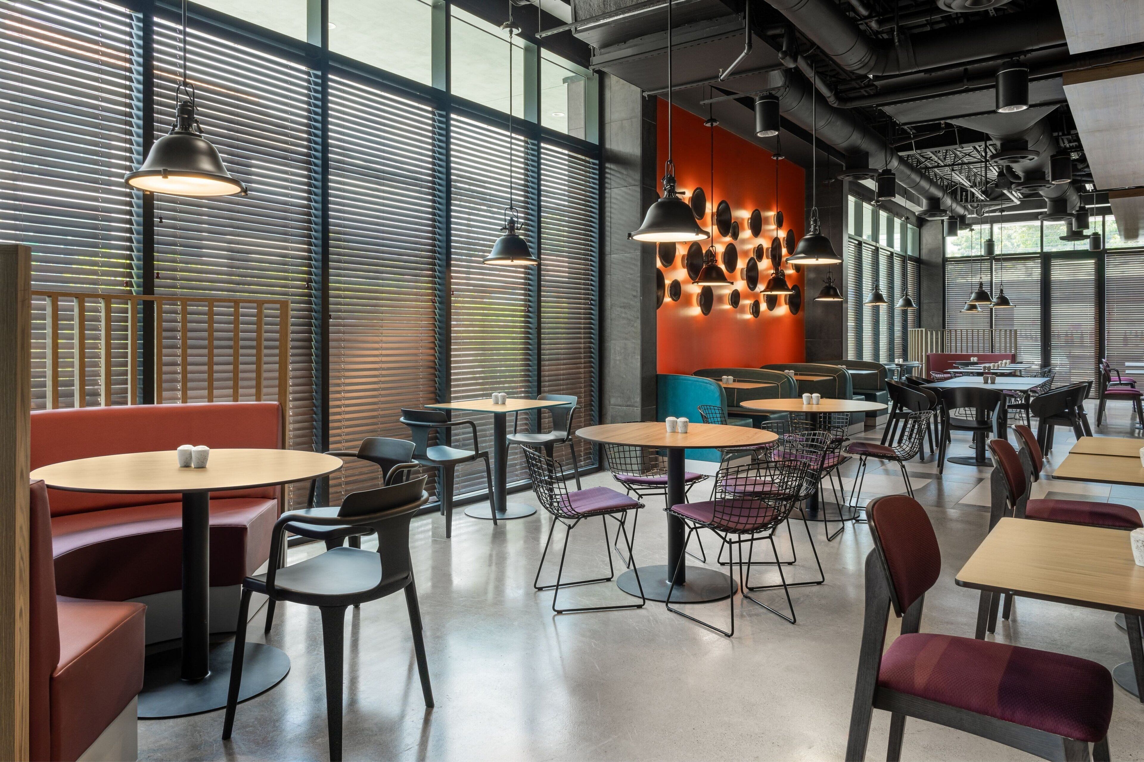 Un intérieur de restaurant moderne avec des tables rondes, des banquettes confortables et des luminaires suspendus.
