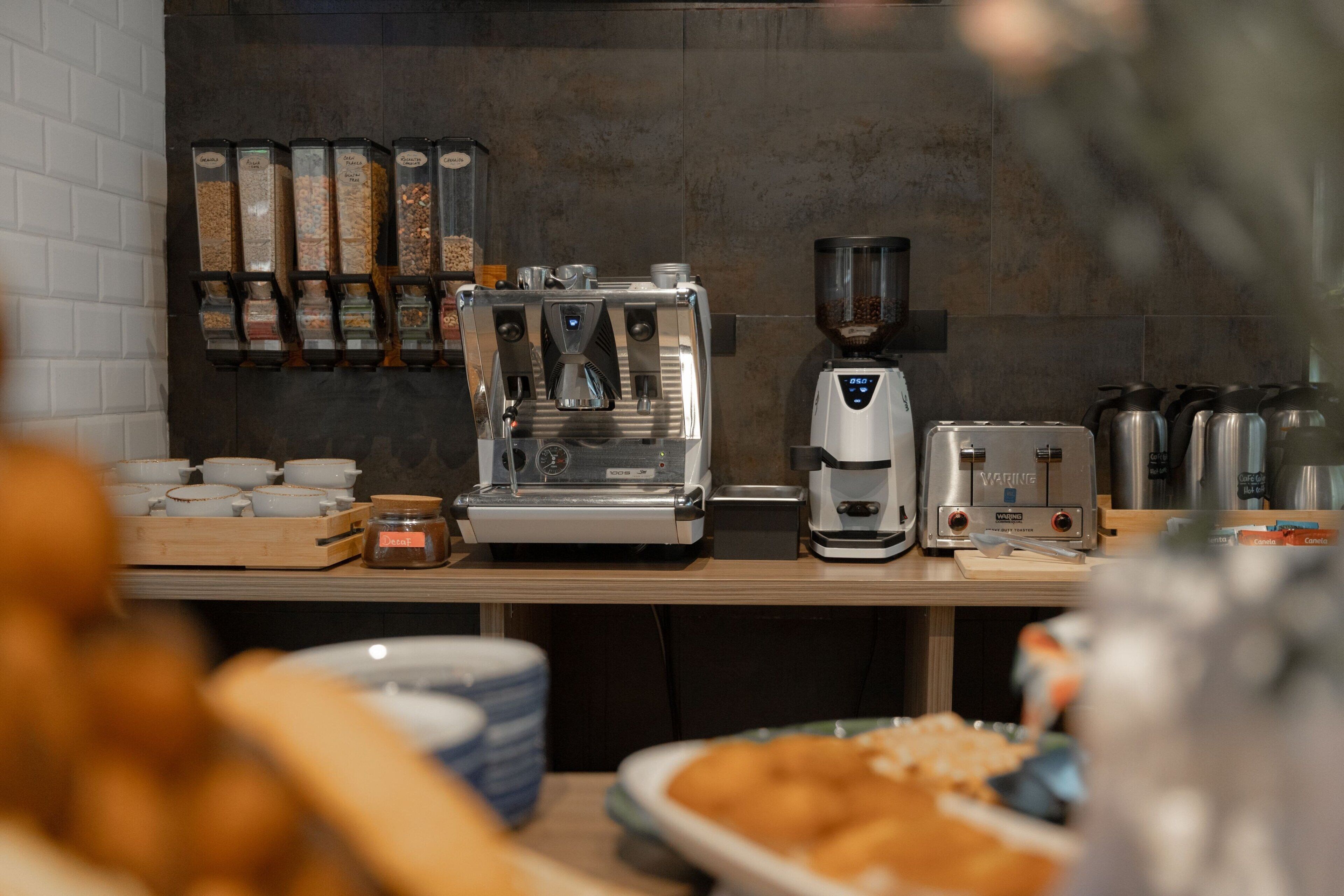 Una estación de café con una máquina de café, un molinillo y diferentes tipos de granos de café.