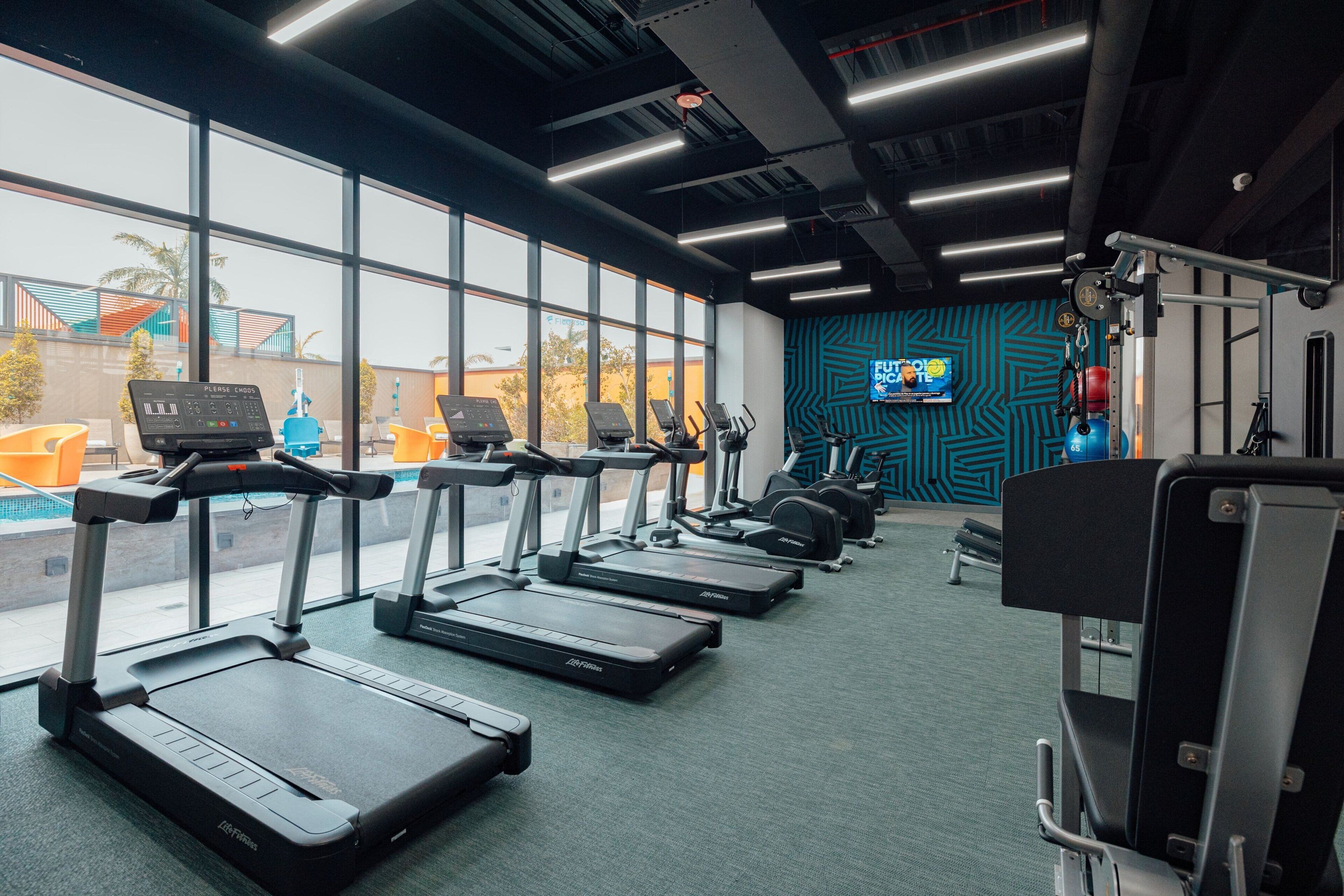 Une salle de sport équipée de tapis de course, de vélos d’exercice et d’appareils de musculation.