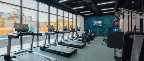 Une salle de sport équipée de tapis de course, de vélos d’exercice et d’appareils de musculation.