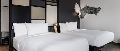 Una habitación de hotel moderna con dos camas, un colorido tapiz a rayas y una original obra de arte en la pared.