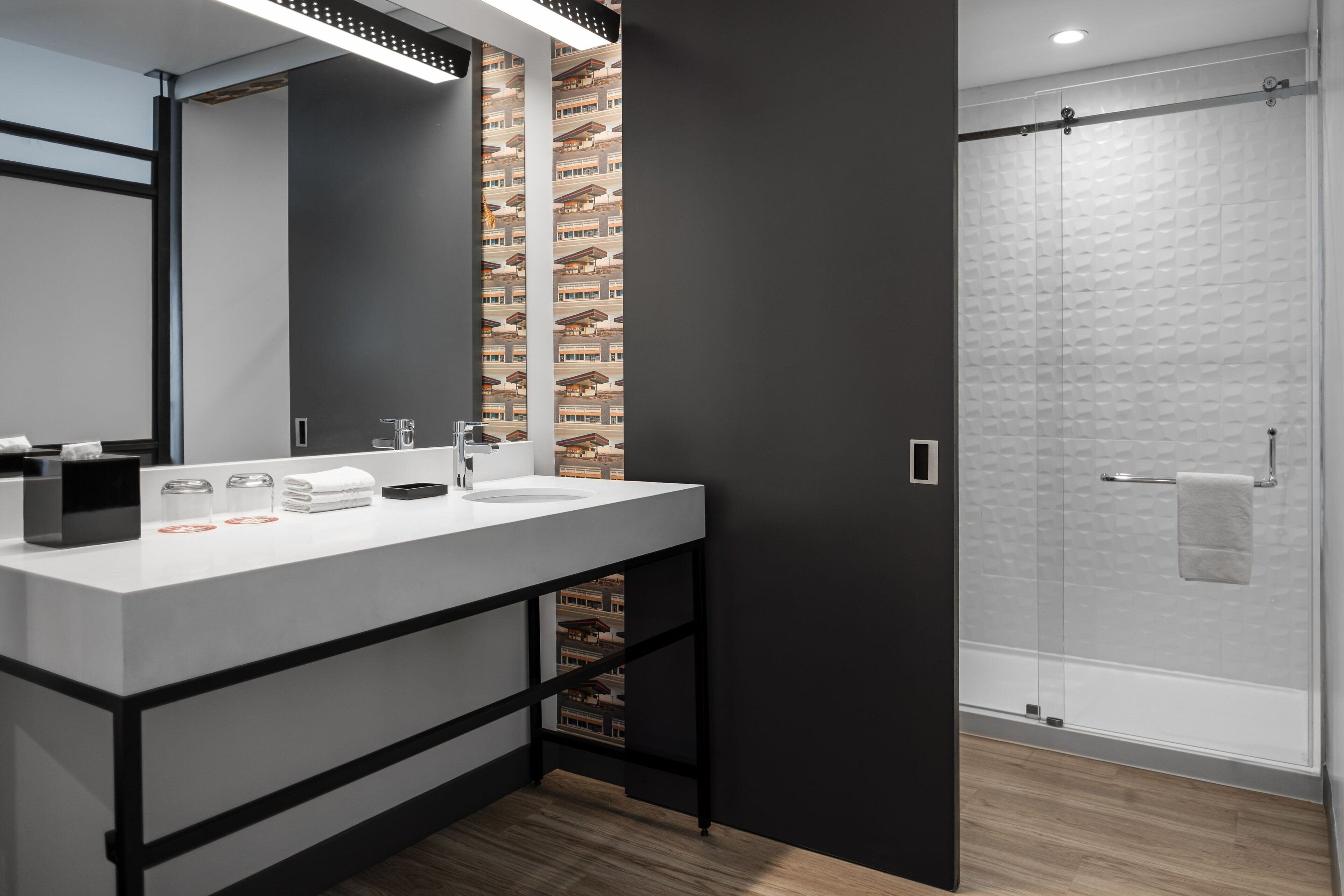 Un baño moderno con un espejo grande, dos lavamanos y una cabina de ducha de vidrio.