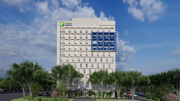 A Holiday Inn Express hotel with a modern design, featuring a large blue section on the facade, surrounded by greenery and a parking area.