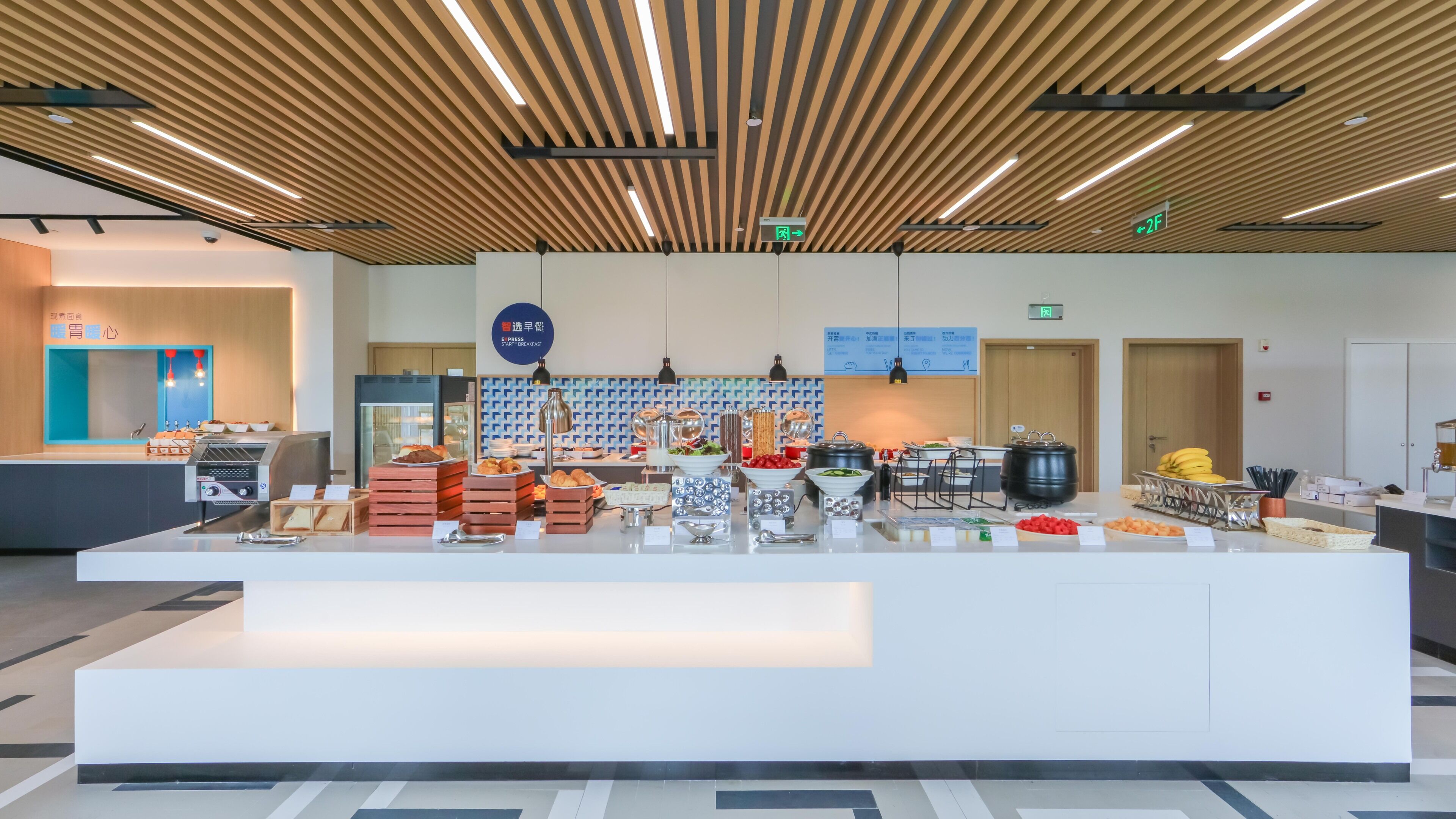 A modern breakfast buffet area with a variety of food options, a coffee machine, and a sign indicating the location of the breakfast room.