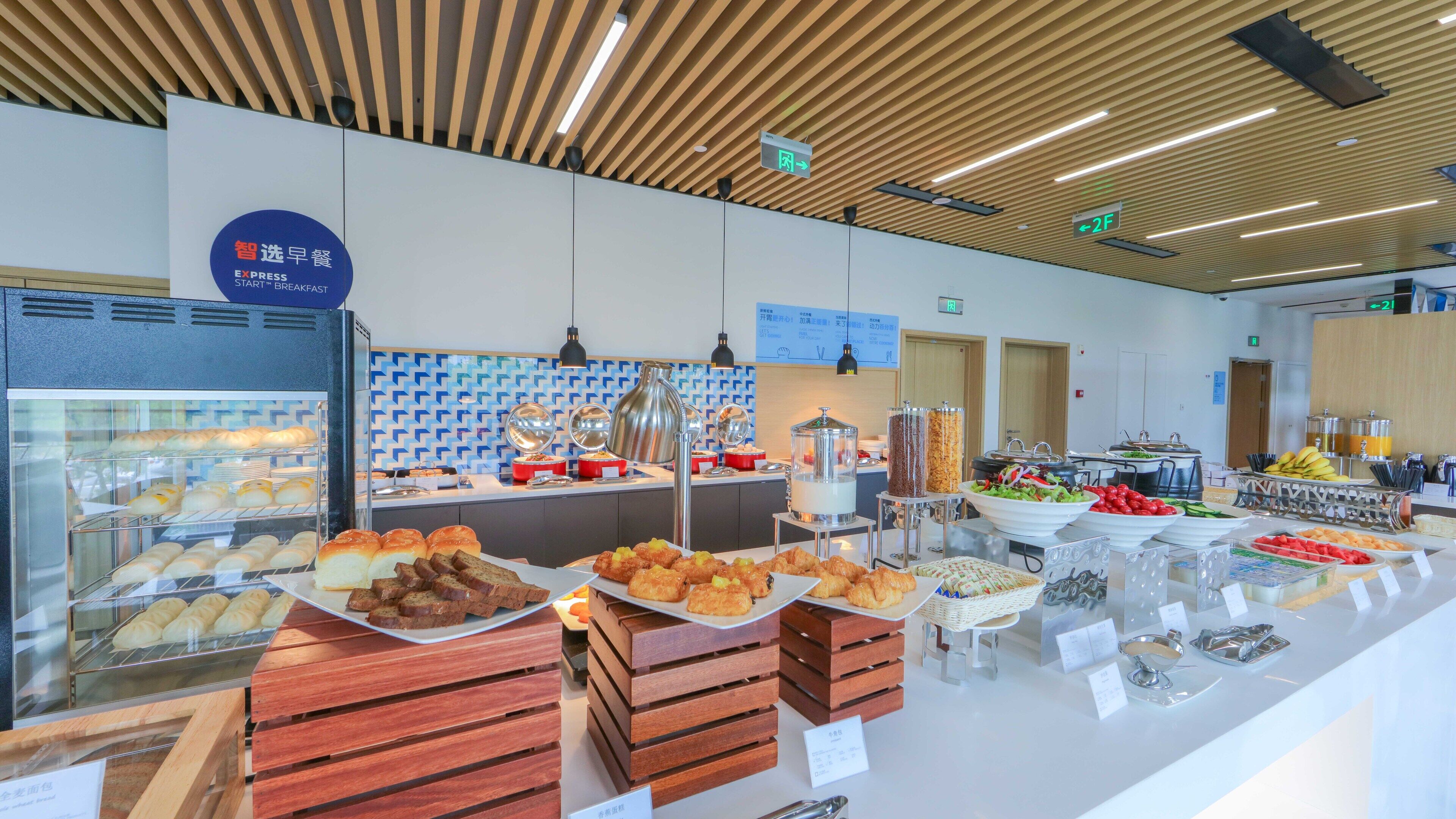 A buffet with various food items and a sign indicating breakfast options.