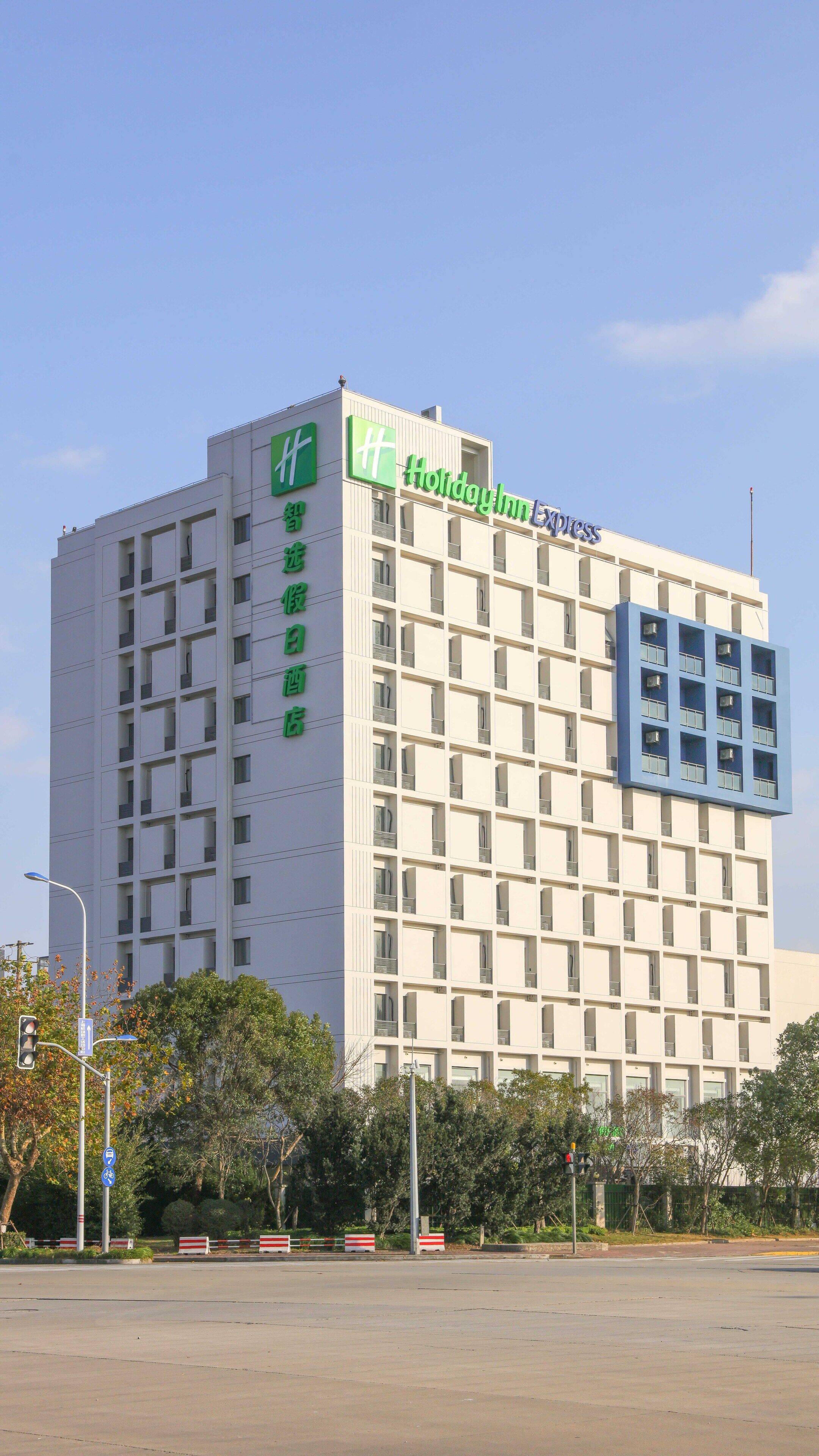 Ein mehrstöckiges Hotel mit einem auffälligen, grün-blauen Schild, das es als Holiday Inn Express kennzeichnet.