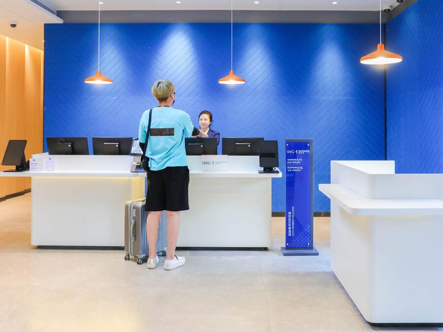 A reception desk with two computer monitors, a blue wall, and a sign indicating IHG Platinum Elite.