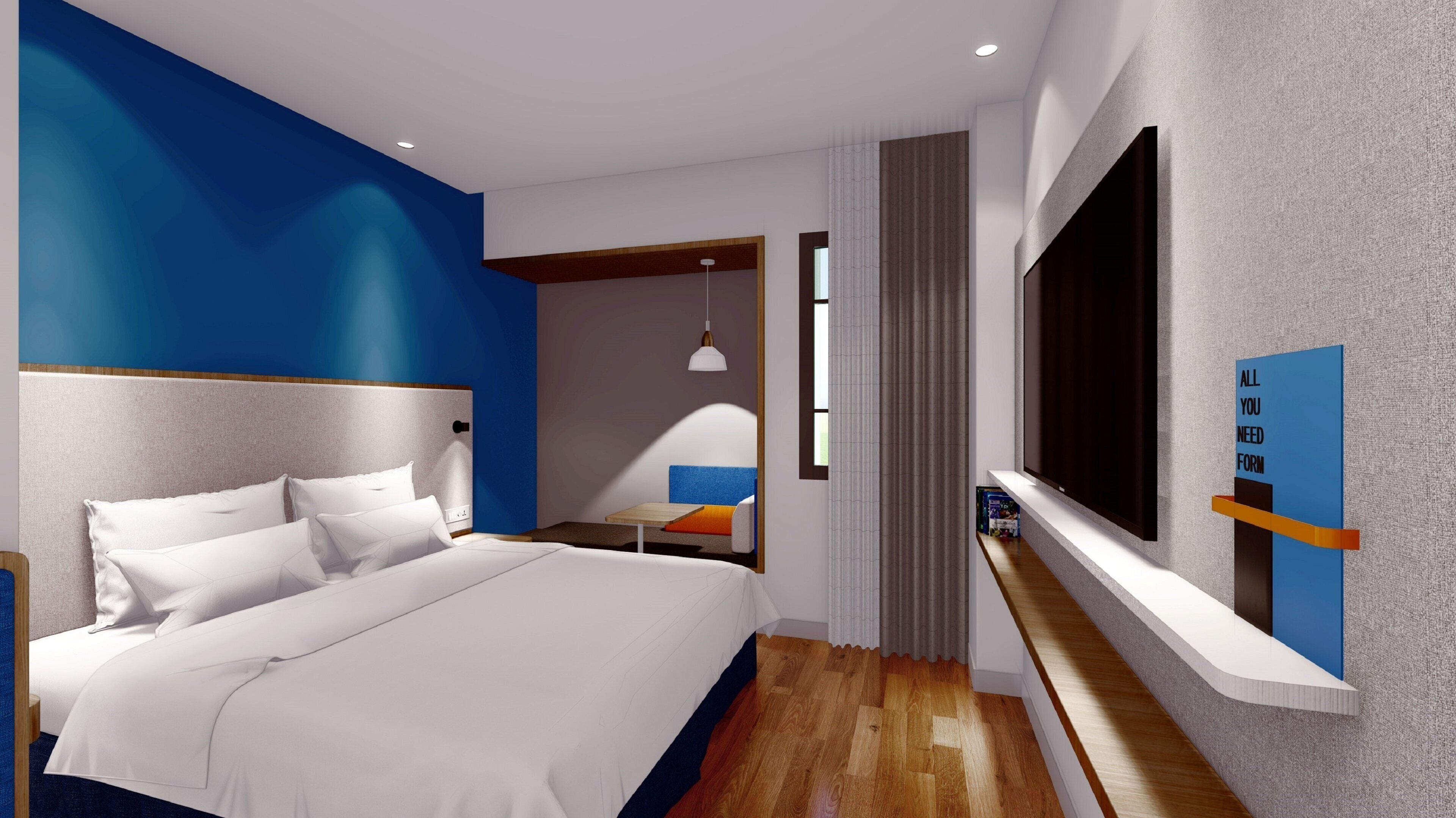 Une chambre d’hôtel moderne dotée d’un grand lit, d’un téléviseur fixé au mur et d’un petit coin salon avec une table et des chaises.
