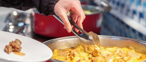 A person serving food from a large pot.