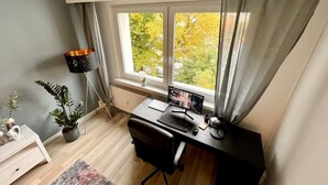 Un espacio de oficina moderno con escritorio, computadora y ventana con vista a árboles.