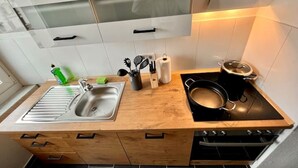 Una cocina moderna con encimera de madera, pileta de acero inoxidable y cocina negra.