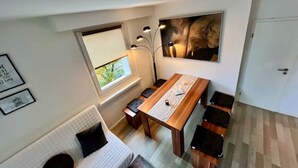 Un espacio habitable compacto con una mesa de comedor, bancos, un sofá y un ventanal grande.