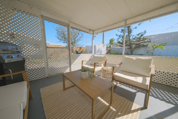 Enjoy al fresco dining and cooking in this patio area, featuring a grill and comfortable seating for two.