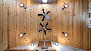 Ein Zimmer mit Holzwandverkleidung, einem Deckenventilator, Einbauleuchten und einem Schild, das es als Token House Building kennzeichnet.