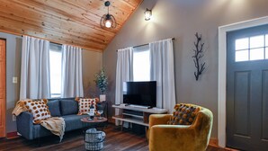 Ein gemütliches Wohnzimmer mit Sofa, Sessel, Fernseher und Holzboden.
