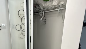 Un baño moderno con mampara de vidrio, un perchero con toallas y un estante con artículos de aseo.