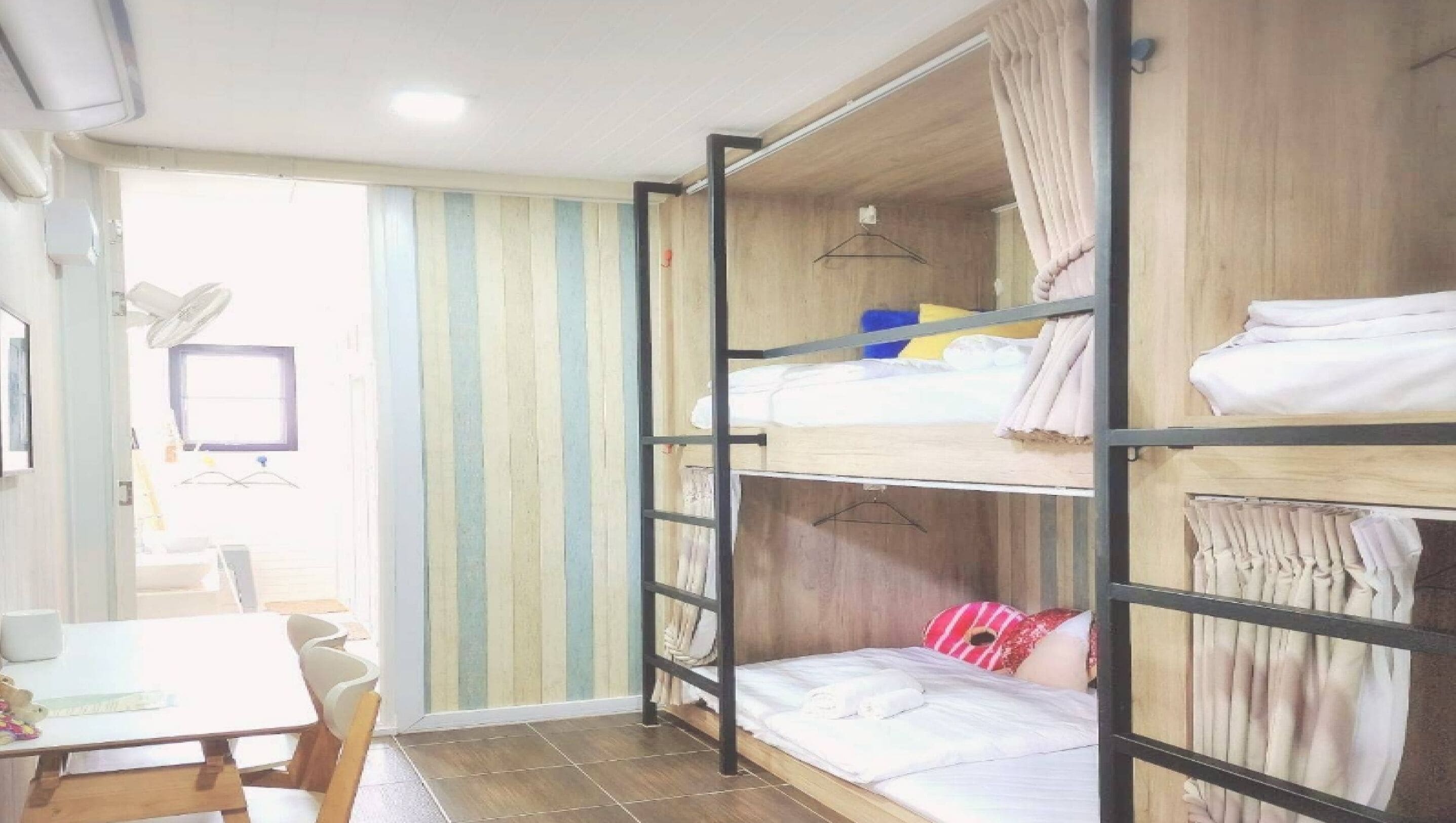 A dormitory room with bunk beds, a desk, and a chair.