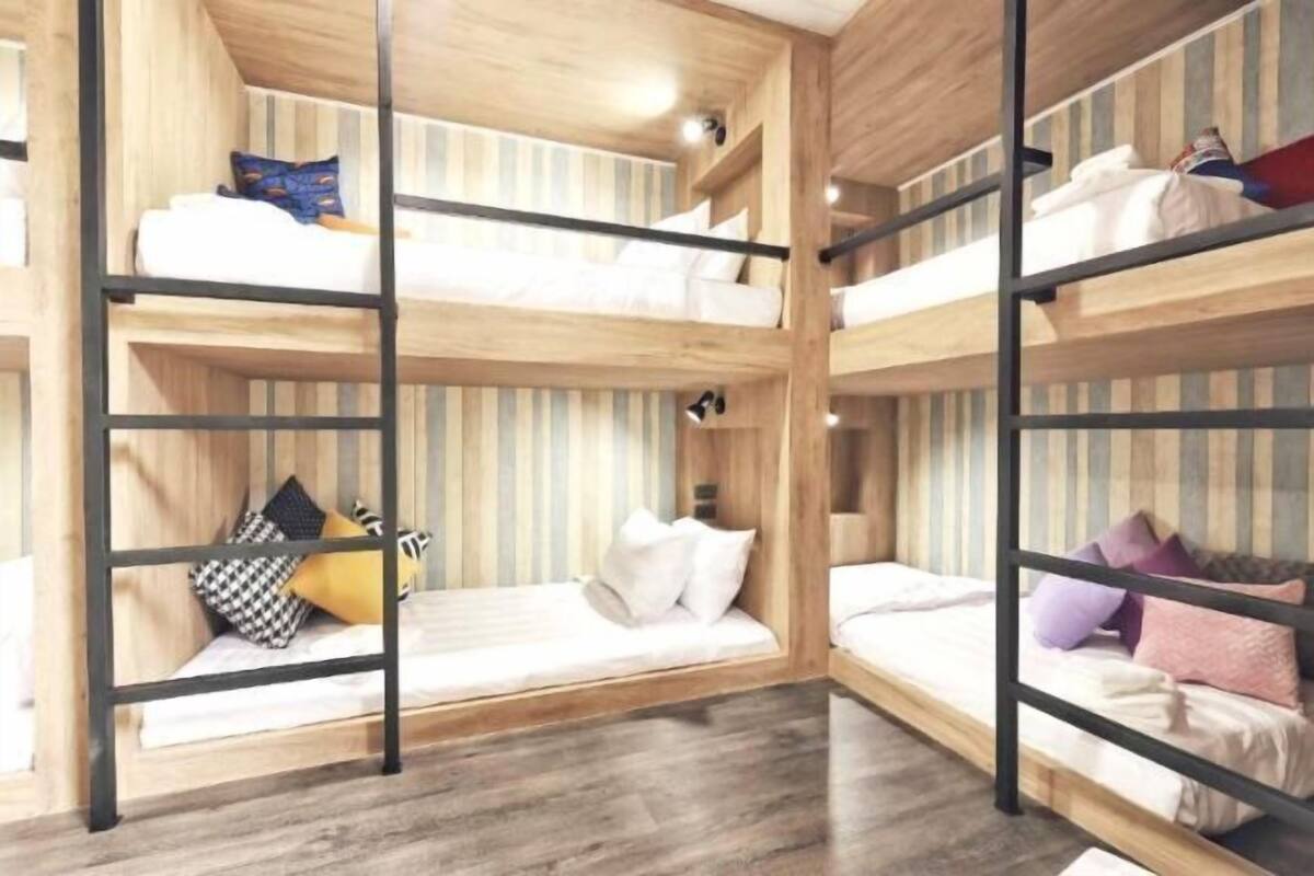 Een slaapkamer met een meerlaags stapelbed, houten wanden en vloeren, met een strepenpatroon op het bovenste bed.