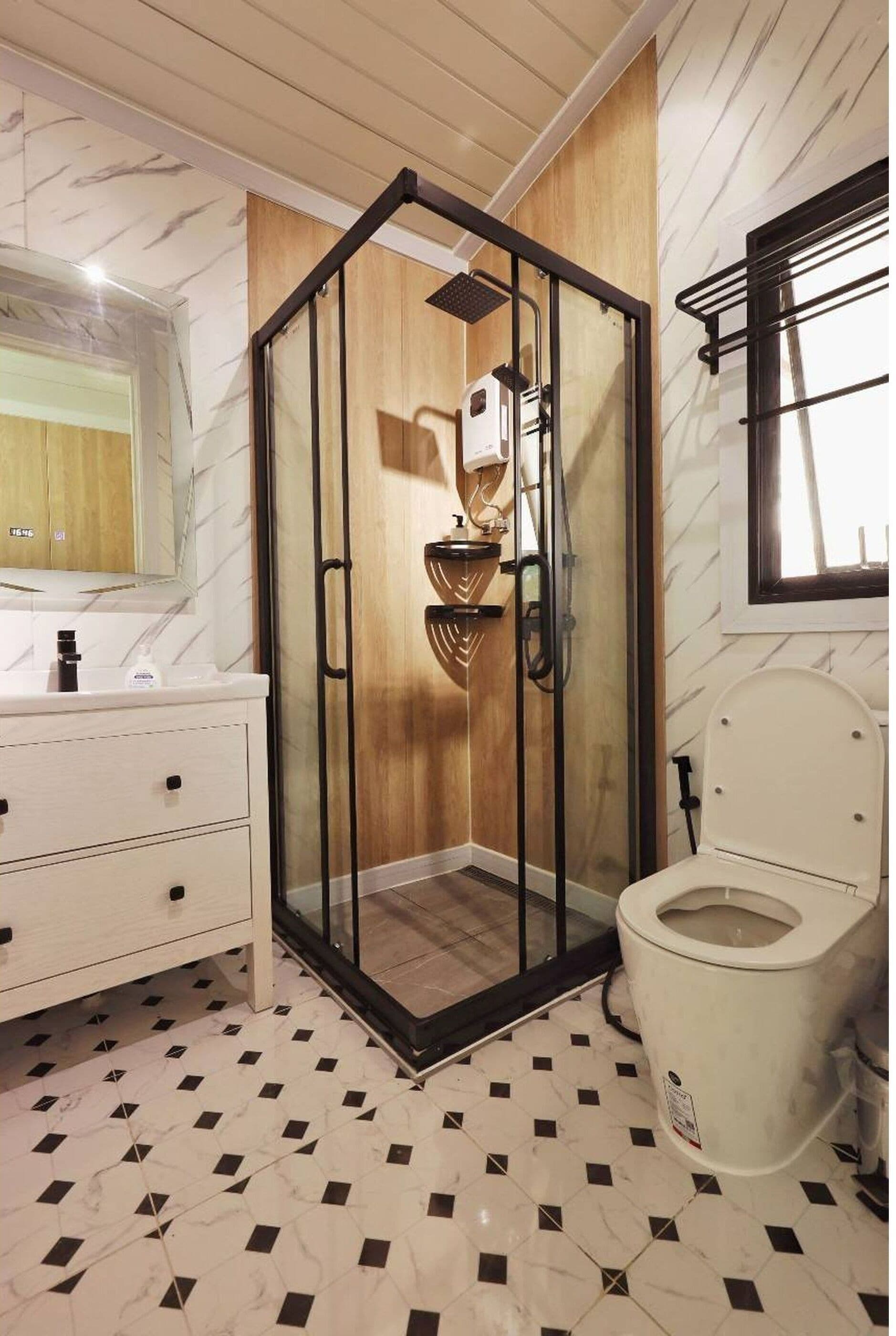 A modern bathroom with a glass-enclosed shower, a white toilet, and a vanity with drawers.