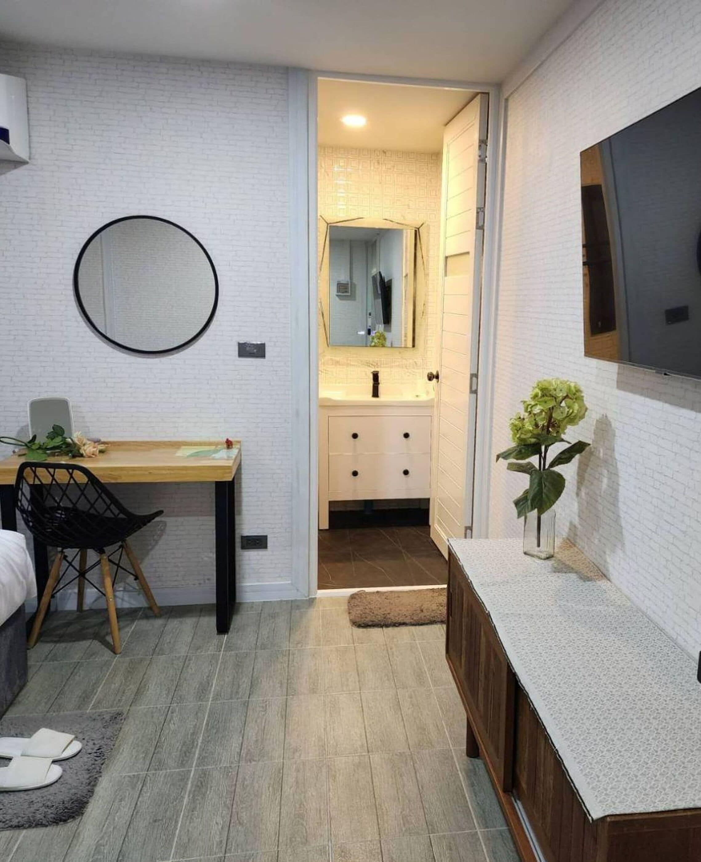 A compact room with a desk, chair, and a small vanity with a mirror.