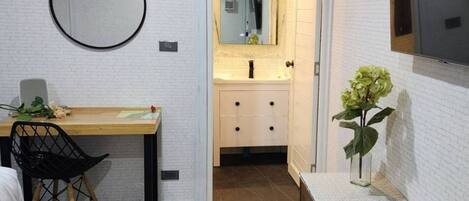 A compact room with a desk, chair, and a small vanity with a mirror.