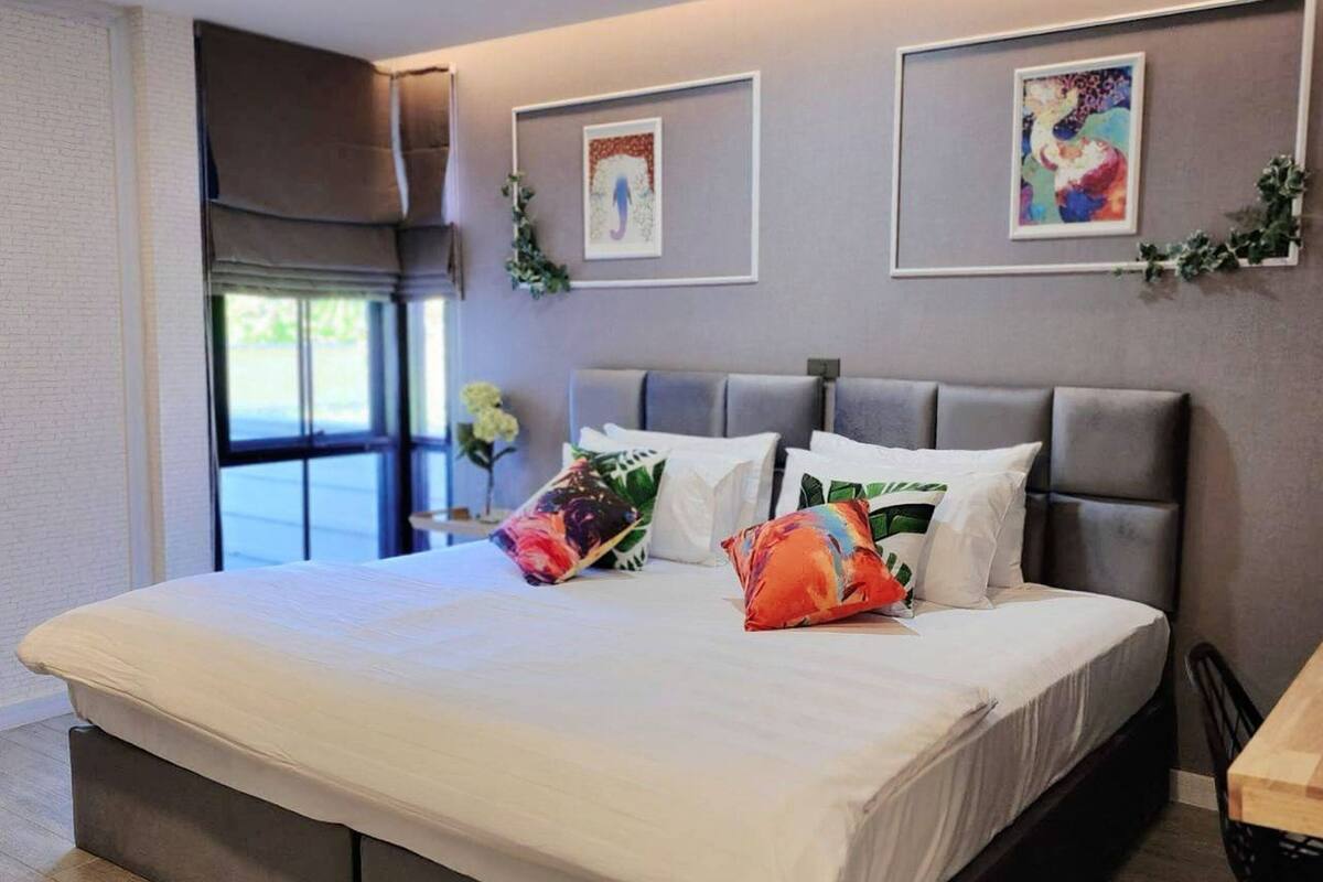 Een moderne slaapkamer met een groot bed, een raam met uitzicht en twee kunstwerken in lijsten aan de muur.