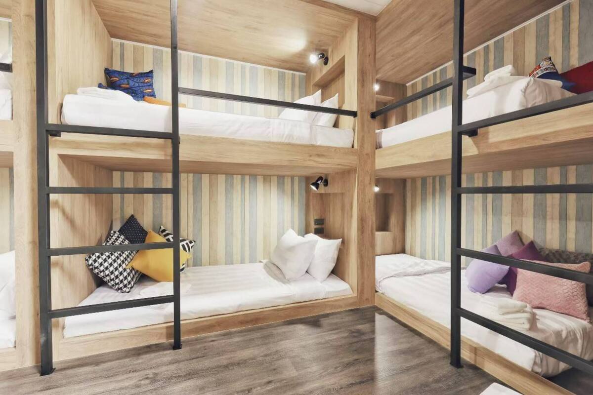 Een slaapkamer met een meerlaags stapelbed, houten wanden en metalen leuningen.